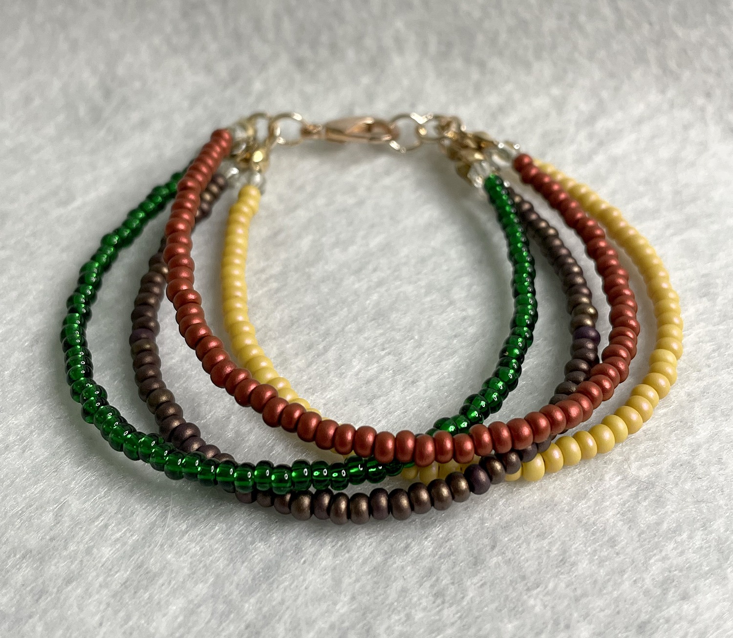 Multi-strand beaded bracelet with green, yellow, red, and brown tiny beads and a metal clasp.